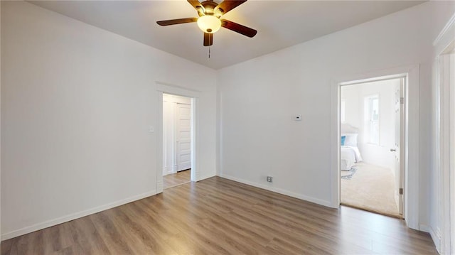 empty room with light wood finished floors, a ceiling fan, and baseboards