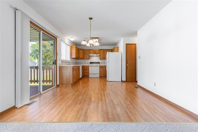 487 Prentice Dr, Ofallon, MO 63376 - kitchen with white appliances, a chandelier, light wood finished floors, brown cabinetry, and light countertops