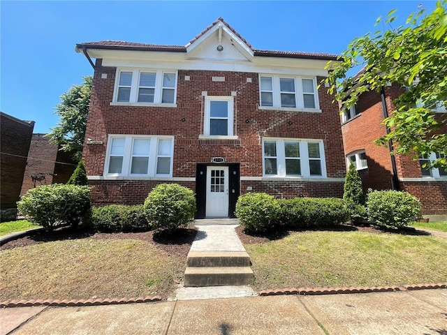 2715 Arkansas Ave, Saint Louis, MO 63118 - view of front of house with brick siding, a tile roof, and a front lawn