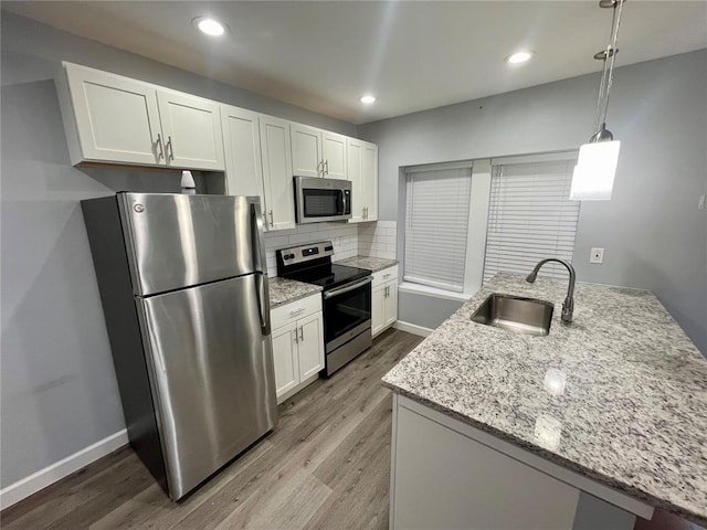 2715 Arkansas Ave, Saint Louis, MO 63118 - kitchen with stainless steel appliances, a sink, wood finished floors, white cabinets, and recessed lighting