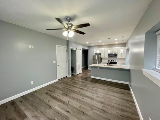 2715 Arkansas Ave, Saint Louis, MO 63118 - kitchen featuring appliances with stainless steel finishes, a barn door, baseboards, white cabinets, and dark wood-style flooring