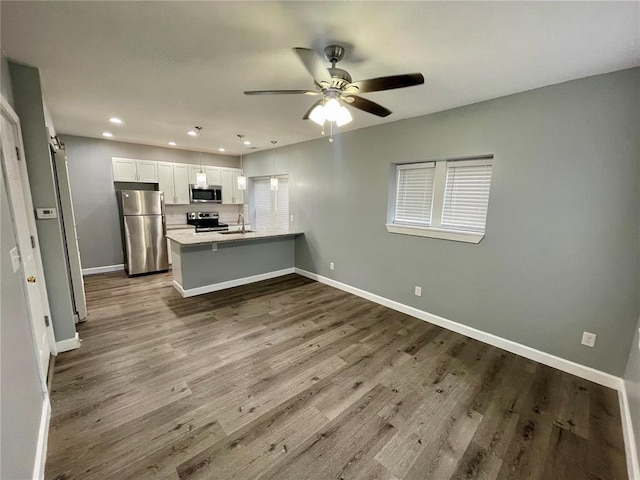 2715 Arkansas Ave, Saint Louis, MO 63118 - kitchen featuring stainless steel appliances, a peninsula, a sink, white cabinets, and a ceiling fan