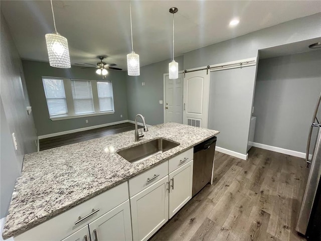 2715 Arkansas Ave, Saint Louis, MO 63118 - kitchen with a sink, stainless steel appliances, a barn door, wood finished floors, and white cabinets