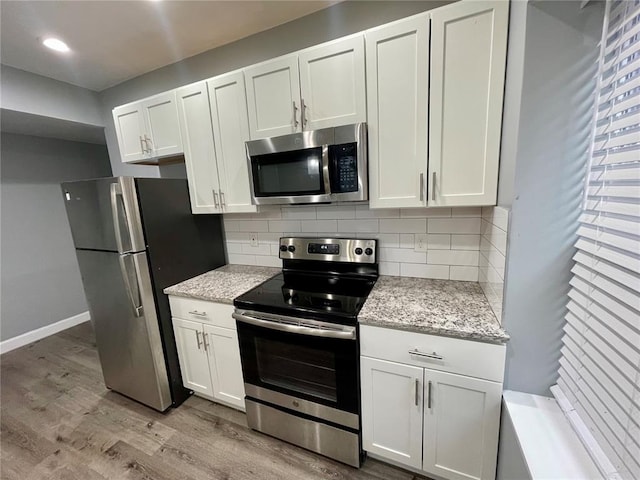 2715 Arkansas Ave, Saint Louis, MO 63118 - kitchen featuring appliances with stainless steel finishes, light wood-type flooring, decorative backsplash, white cabinets, and baseboards