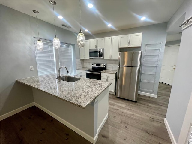 2715 Arkansas Ave, Saint Louis, MO 63118 - kitchen featuring stainless steel appliances, a sink, light stone countertops, white cabinets, and wood finished floors
