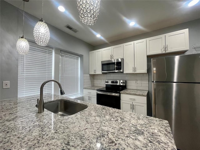 2715 Arkansas Ave, Saint Louis, MO 63118 - kitchen featuring stainless steel appliances, a sink, backsplash, white cabinets, and light stone counters
