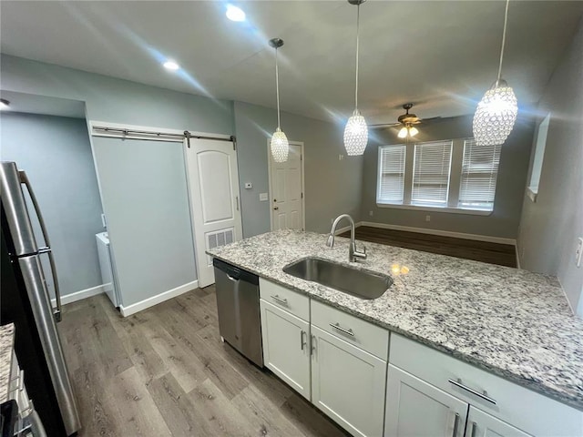 2715 Arkansas Ave, Saint Louis, MO 63118 - kitchen featuring appliances with stainless steel finishes, a sink, light wood finished floors, a barn door, and ceiling fan