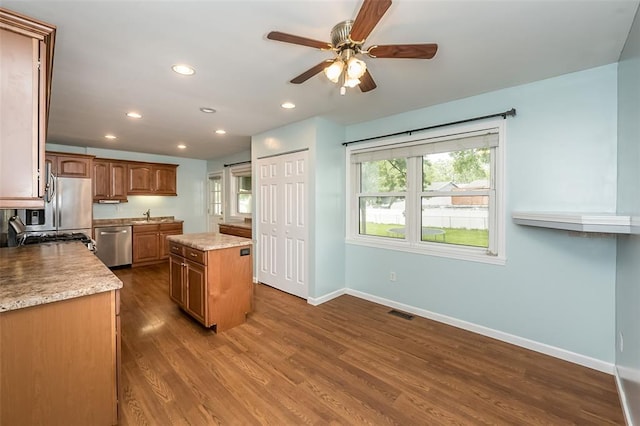 kitchen with stainless steel dishwasher, baseboards, a kitchen island, a ceiling fan, and dark wood-style floors