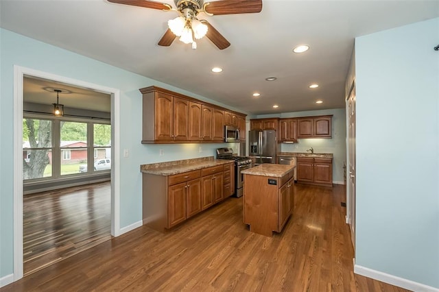 kitchen featuring appliances with stainless steel finishes, baseboards, a center island, recessed lighting, and dark wood-style flooring
