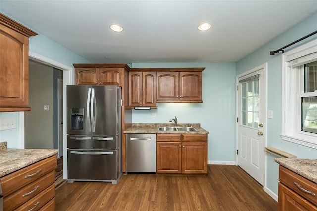 kitchen featuring stainless steel appliances, a sink, dark wood-type flooring, recessed lighting, and brown cabinets