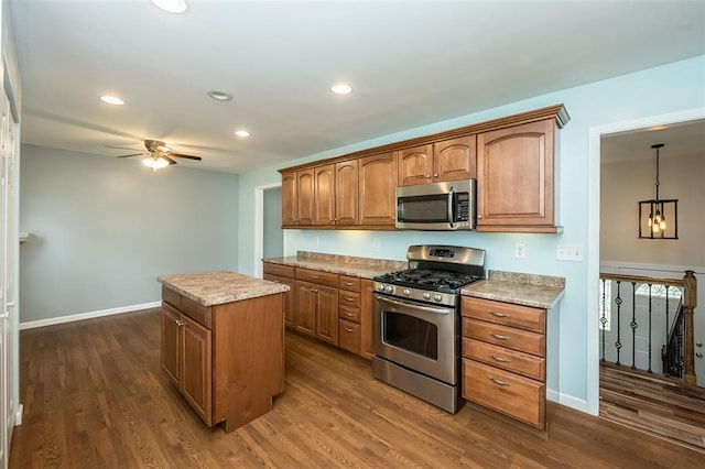 kitchen featuring appliances with stainless steel finishes, a ceiling fan, a center island, dark wood-type flooring, and recessed lighting