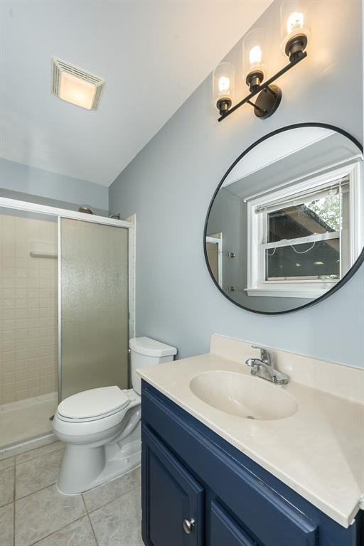 full bath with a stall shower, toilet, vanity, and tile patterned floors