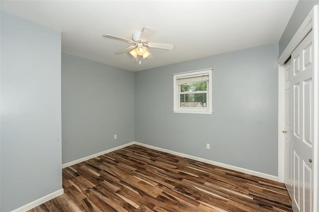 unfurnished bedroom featuring a closet, dark wood-style floors, baseboards, and a ceiling fan
