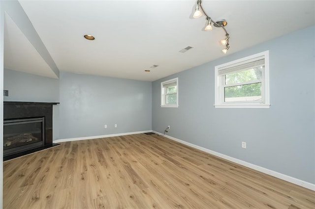 unfurnished living room featuring baseboards, light wood-style flooring, and a glass covered fireplace
