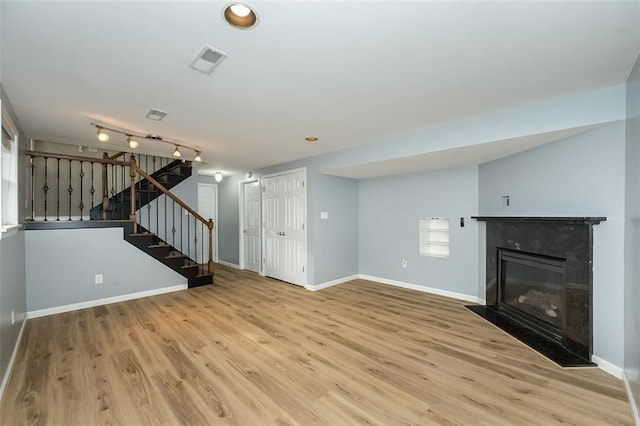 unfurnished living room with baseboards, stairs, wood finished floors, and a fireplace