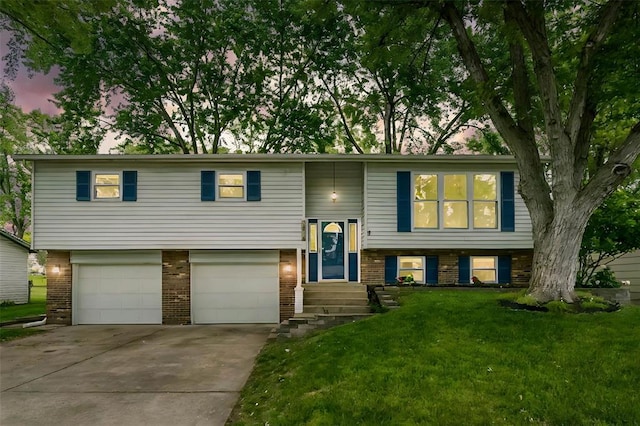 bi-level home featuring brick siding, an attached garage, concrete driveway, a front yard, and entry steps