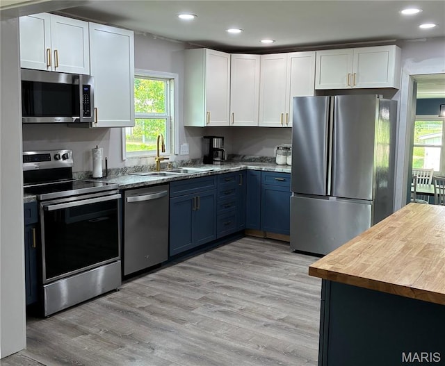 127 E 2nd St, De Soto, MO 63020 - kitchen with stainless steel appliances, blue cabinets, white cabinetry, recessed lighting, and light wood finished floors