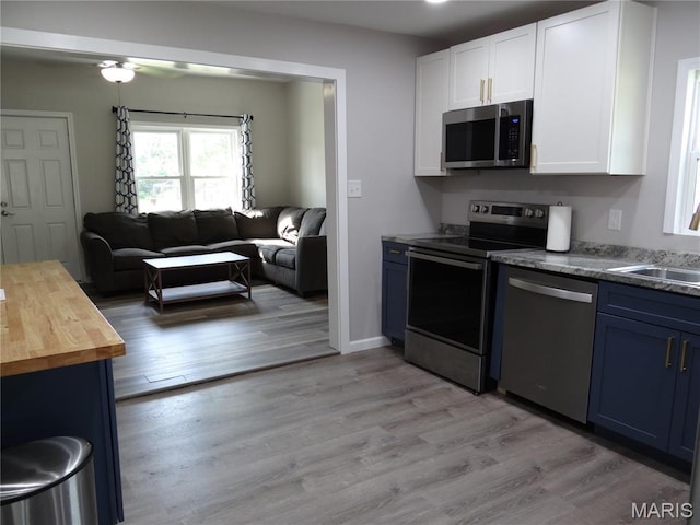127 E 2nd St, De Soto, MO 63020 - kitchen featuring appliances with stainless steel finishes, butcher block counters, white cabinetry, open floor plan, and light wood-style flooring