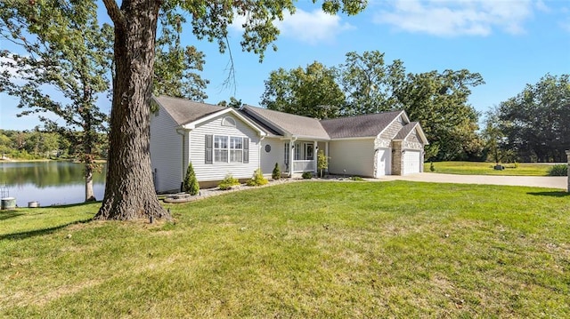 ranch-style house with a garage, concrete driveway, a front yard, and a water view