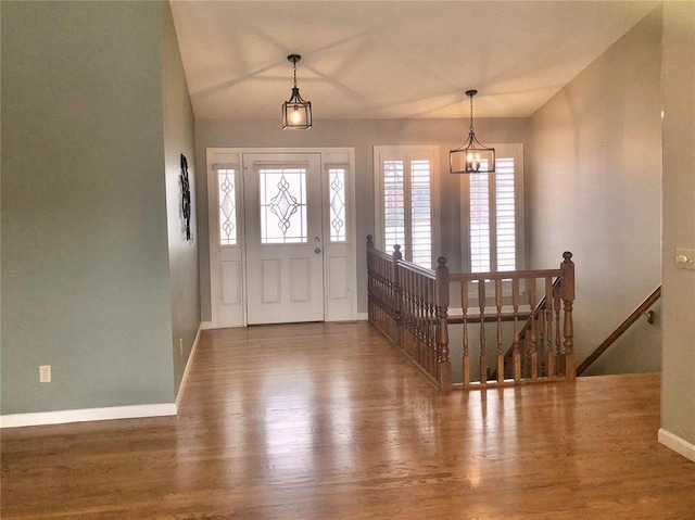 foyer entrance featuring wood finished floors, baseboards, and a chandelier