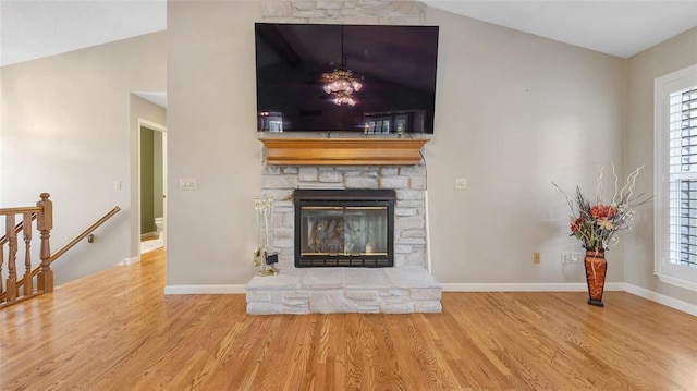 unfurnished living room featuring lofted ceiling, wood finished floors, baseboards, and healthy amount of natural light