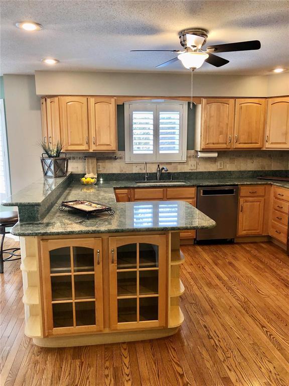 kitchen featuring dishwasher, a sink, open shelves, light brown cabinets, and wood finished floors