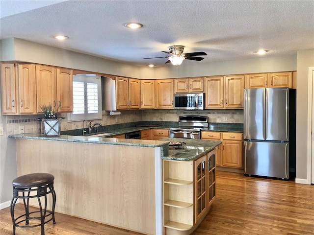 kitchen featuring stainless steel appliances, a sink, ceiling fan, backsplash, and open shelves