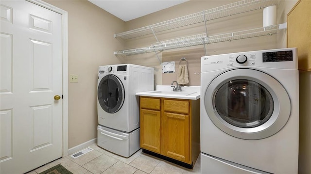 washroom with light tile patterned floors, washer and clothes dryer, baseboards, and cabinet space