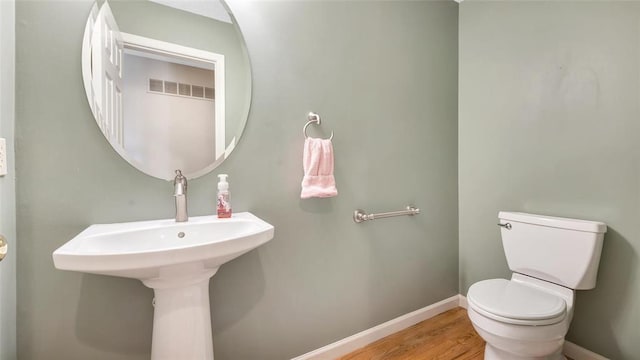 bathroom featuring toilet, baseboards, and wood finished floors