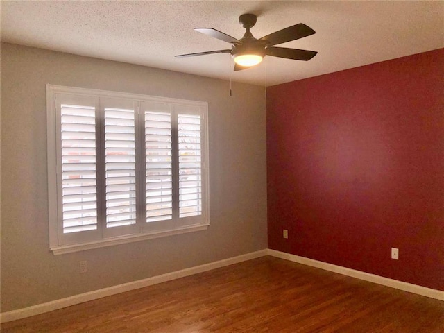 spare room featuring healthy amount of natural light, wood finished floors, a ceiling fan, a textured ceiling, and baseboards