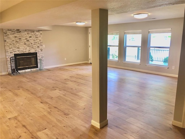 unfurnished living room featuring wood-type flooring, baseboards, and a fireplace