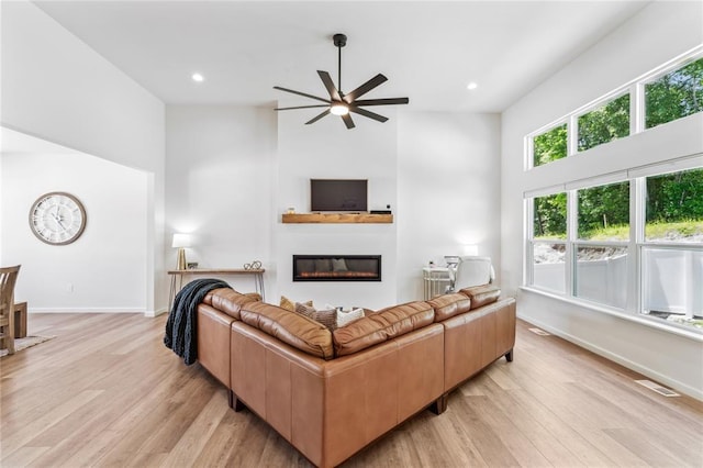 1513 Grey Wolf Dr, Imperial, MO 63052 - living area featuring a towering ceiling, ceiling fan, a glass covered fireplace, light wood finished floors, and baseboards