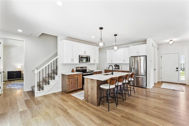 1513 Grey Wolf Dr, Imperial, MO 63052 - kitchen with appliances with stainless steel finishes, a sink, a breakfast bar, light wood-style flooring, and tasteful backsplash