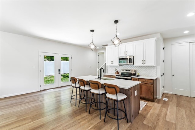 1513 Grey Wolf Dr, Imperial, MO 63052 - kitchen with stainless steel appliances, a sink, a center island with sink, tasteful backsplash, and light wood-type flooring
