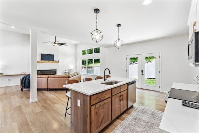 1513 Grey Wolf Dr, Imperial, MO 63052 - kitchen featuring stainless steel dishwasher, a sink, a breakfast bar area, brown cabinetry, and a glass covered fireplace
