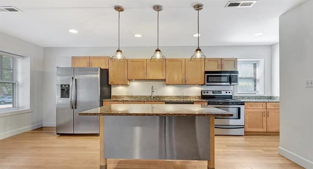 4220 Mcpherson Unit 101, Saint Louis, MO 63108 - kitchen with appliances with stainless steel finishes, dark stone countertops, light wood-style flooring, a kitchen island, and baseboards