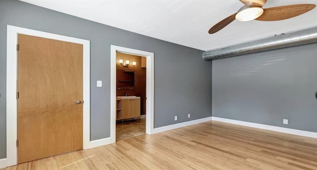 4220 Mcpherson Unit 101, Saint Louis, MO 63108 - unfurnished bedroom featuring wood finished floors, baseboards, connected bathroom, a sink, and ceiling fan