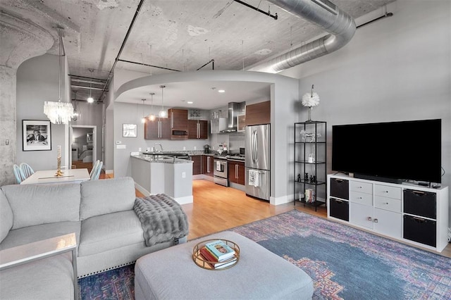 4100 Forest Park Ave Unit 323, Saint Louis, MO 63108 - living area with a chandelier, light wood-style floors, baseboards, and arched walkways