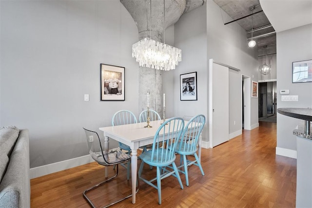 4100 Forest Park Ave Unit 323, Saint Louis, MO 63108 - dining area with a chandelier, a towering ceiling, wood finished floors, and baseboards
