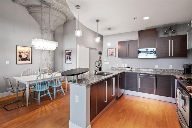 4100 Forest Park Ave Unit 323, Saint Louis, MO 63108 - kitchen with a sink, appliances with stainless steel finishes, light wood-type flooring, a peninsula, and a chandelier