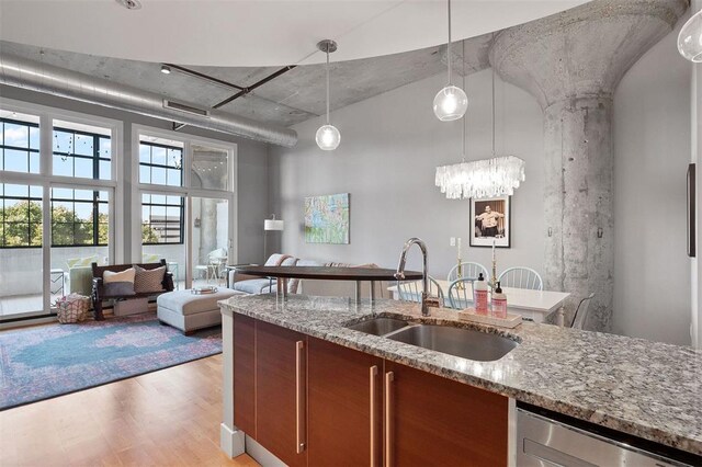 4100 Forest Park Ave Unit 323, Saint Louis, MO 63108 - kitchen featuring a sink, dishwasher, open floor plan, light wood-style floors, and light stone countertops