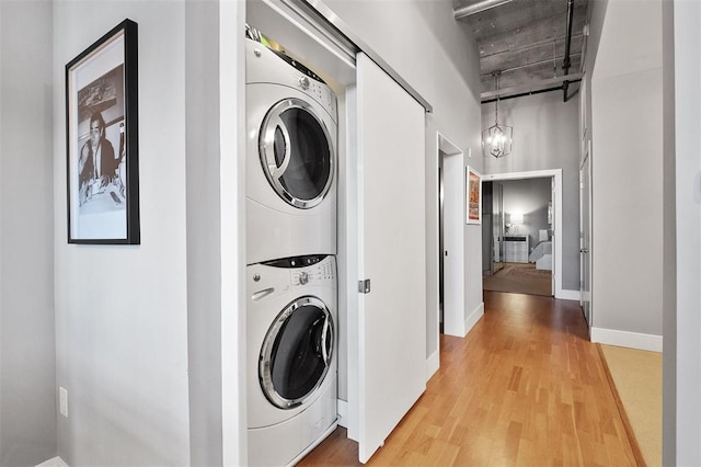 4100 Forest Park Ave Unit 323, Saint Louis, MO 63108 - laundry room with stacked washer and clothes dryer, light wood finished floors, and a chandelier