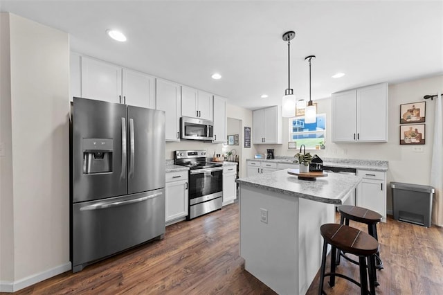 224 Quiet Bend Dr, Wentzville, MO 63385 - kitchen featuring stainless steel appliances, a kitchen bar, dark wood-type flooring, white cabinetry, and a center island
