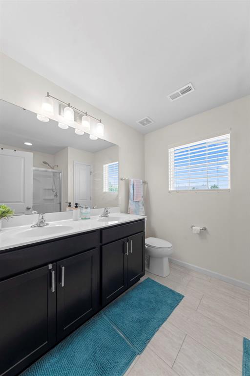224 Quiet Bend Dr, Wentzville, MO 63385 - bathroom with double vanity, plenty of natural light, a shower with door, and toilet