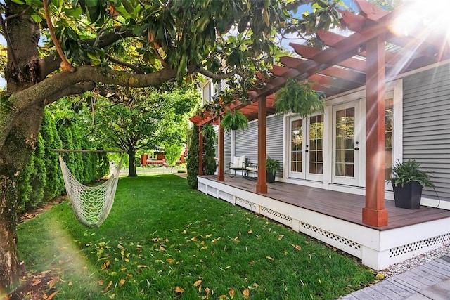 view of grassy yard with a pergola, a wooden deck, and french doors