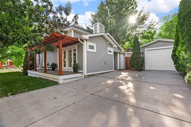 view of front facade with driveway, a chimney, a pergola, a detached garage, and french doors
