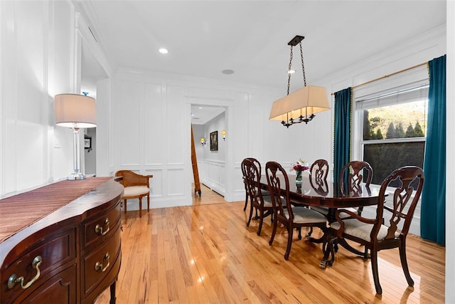 dining space with a decorative wall, ornamental molding, light wood-style flooring, a chandelier, and recessed lighting