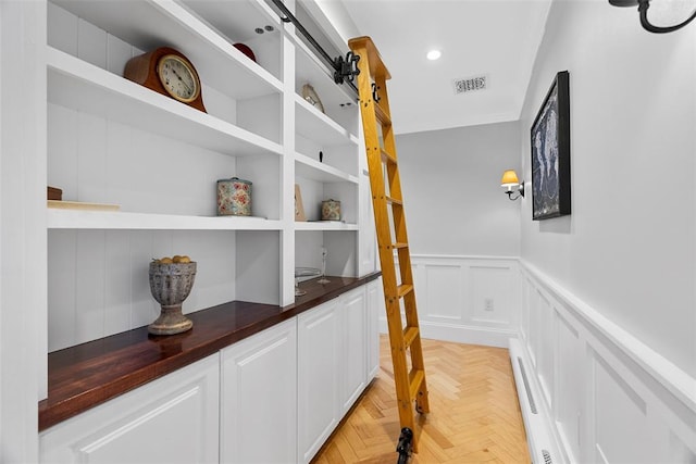 hallway with a baseboard radiator, a decorative wall, wainscoting, and recessed lighting