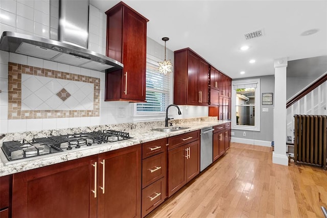 kitchen with wall chimney range hood, radiator heating unit, a sink, stainless steel appliances, and dark brown cabinets