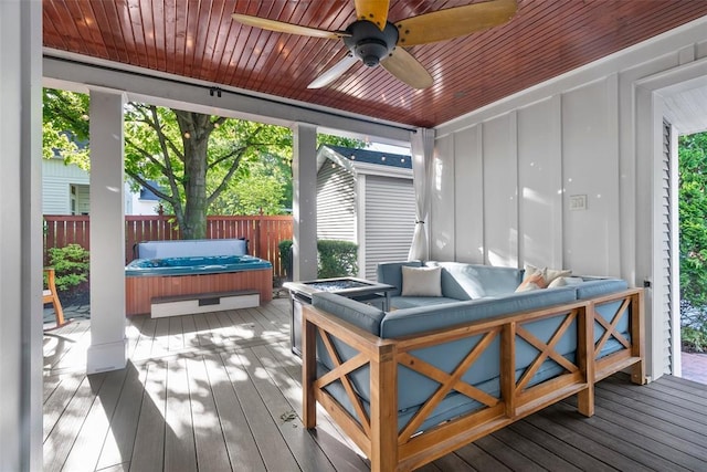 wooden deck featuring a hot tub, ceiling fan, fence, and an outdoor living space